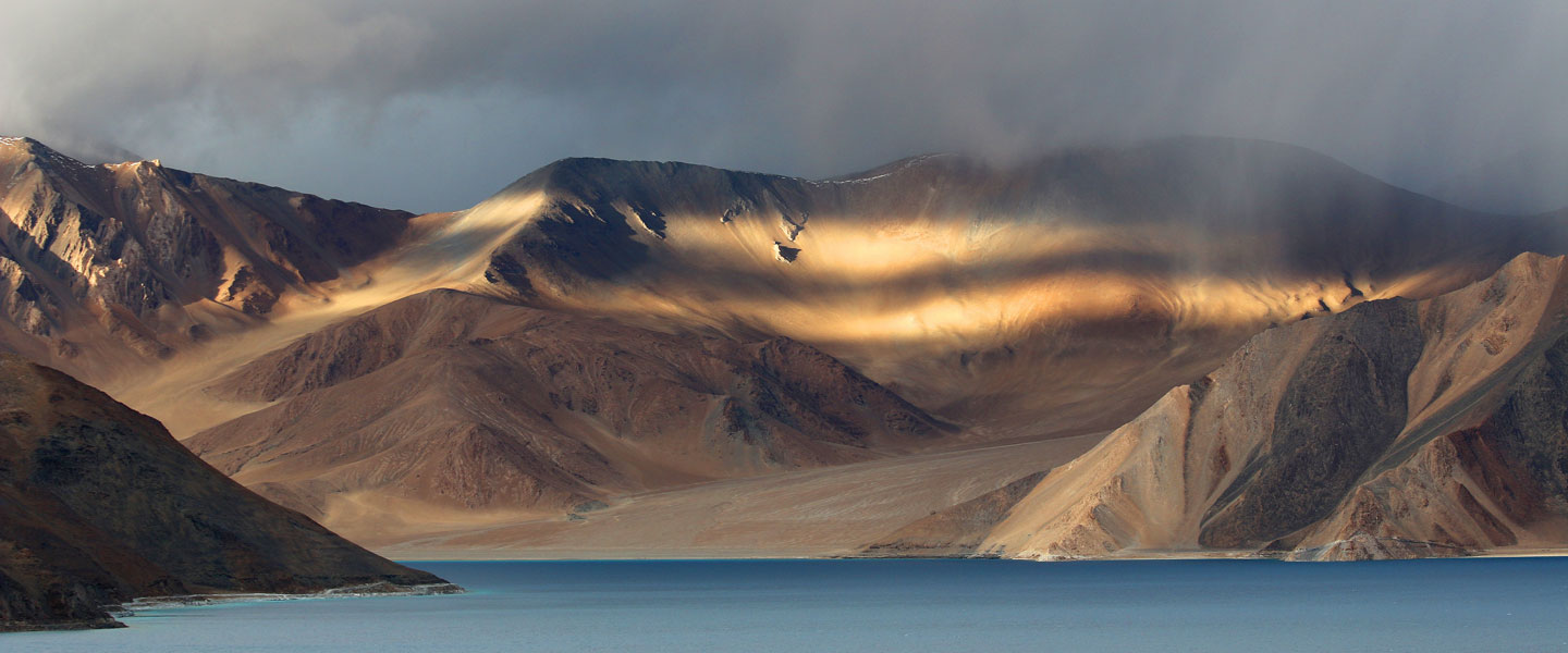 Desert-like mountains descending to a still blue lake